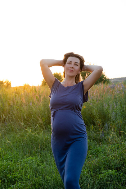 Hamileliğin ve hamileliğin kutlu olsun. Dışarıda parkta poz veren uzun mavi elbiseli hamile beyaz kadın portresi. Güzel, kadınsı, hamile bayan.. - Fotoğraf, Görsel