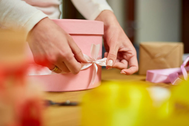 Hands of unrecognisable woman wrapping with ribbon a pink present, gift box, christmas or other holiday handmade present, Making bow at present box, decoration of gift - Φωτογραφία, εικόνα