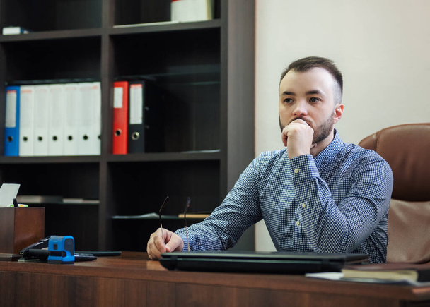 Молодий бізнесмен у сорочці, що працює на ноутбуці в офісі
 - Фото, зображення