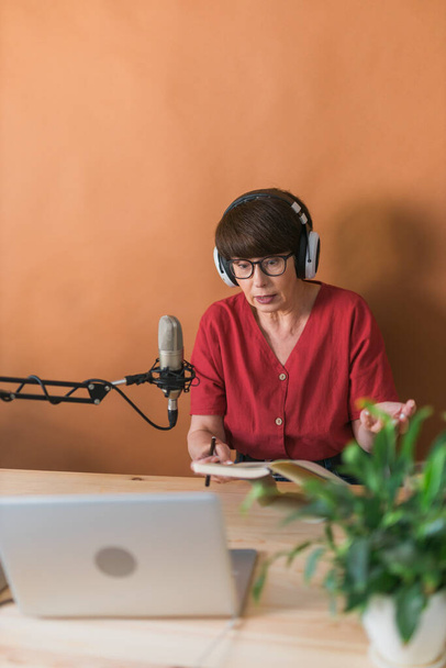Πορτρέτο της ώριμης γυναίκας φορώντας ακουστικά και μιλώντας σε απευθείας σύνδεση ραδιοφωνικό σταθμό - podcast και εκπομπή έννοια - Φωτογραφία, εικόνα