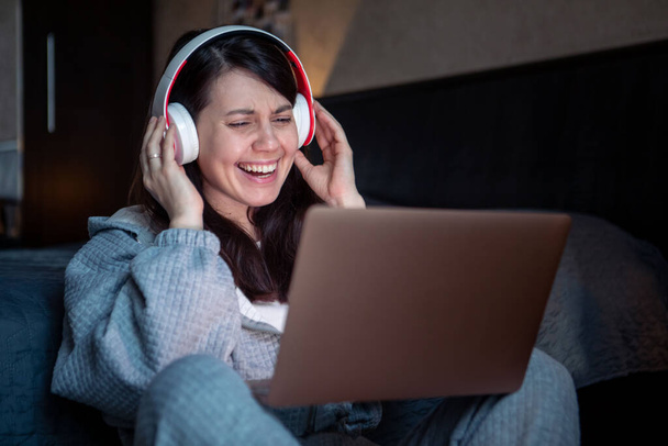 mujer en auriculares que trabajan en el ordenador portátil tiene videollamada trabajo remoto desde casa - Foto, Imagen