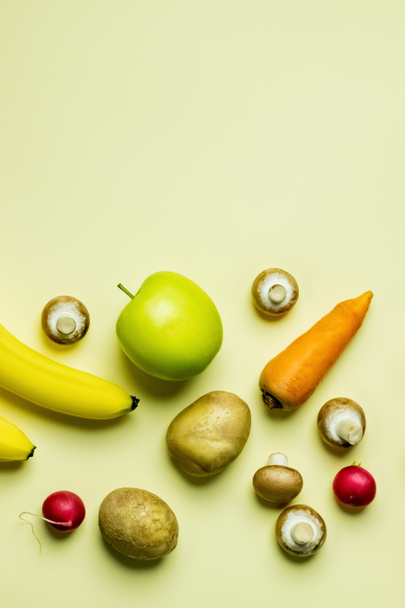 Top view of whole vegetables near fruits on yellow background with copy space - Fotó, kép