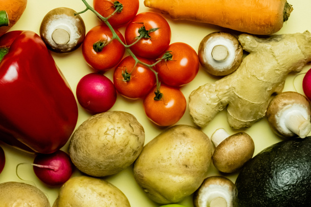 Draufsicht auf natürliches Gemüse und Avocado auf gelbem Hintergrund  - Foto, Bild