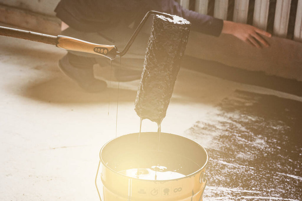 Applying hot resin to the floor for waterproofing, roller and bucket of resin, black and liquid resin. - Foto, Imagem