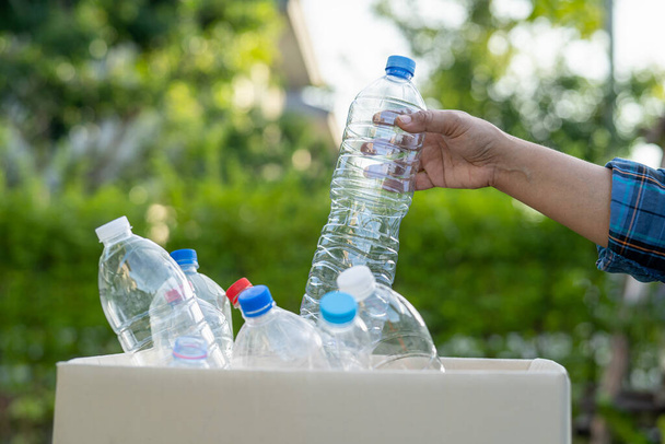 Asyalı bir kadın gönüllü olarak parkta çöp kutusuna su şişeleri taşır, atık çevre ekolojisi kavramını geri dönüştürür.. - Fotoğraf, Görsel
