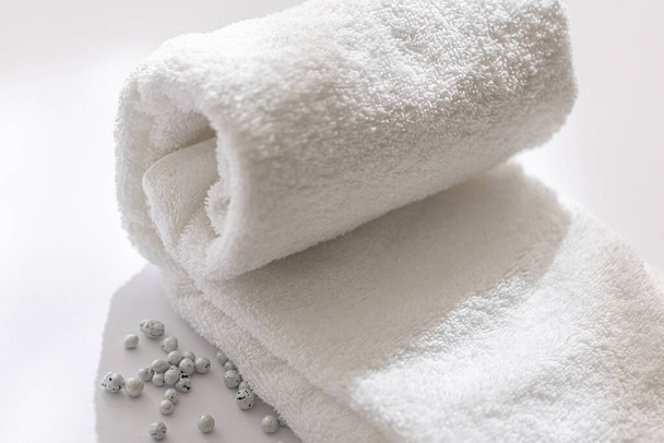 Gros plan d'une serviette de bain blanche roulée sur fond blanc. - Photo, image