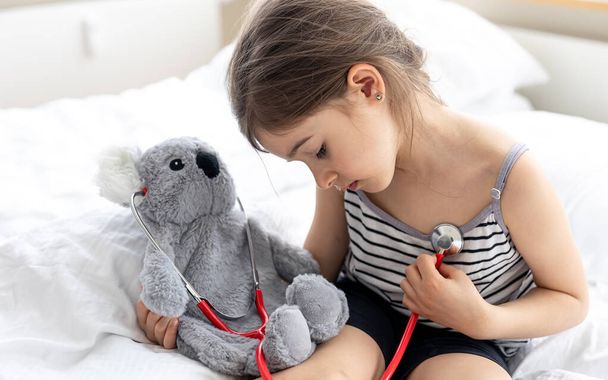 gelukkig klein meisje met zacht speelgoed koala in bed. - Foto, afbeelding