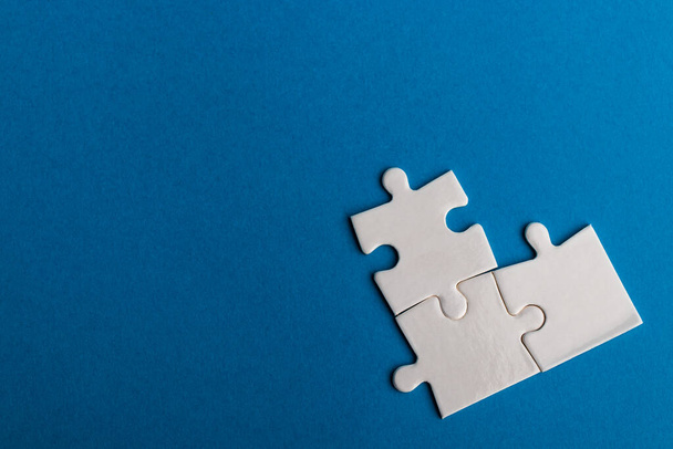 White jigsaw puzzle pieces on blue background. Texture photo with space for text. Teamwork conceptual photo. - Фото, изображение