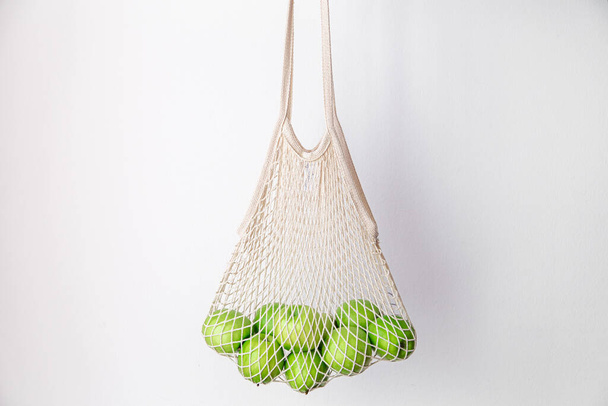 Witte string tas met groene appels op een witte achtergrond. - Foto, afbeelding