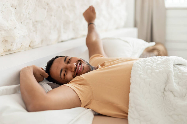 Happy Arabic Male Awakening Yawning Stretching Arms Lying In Bedroom - Photo, Image
