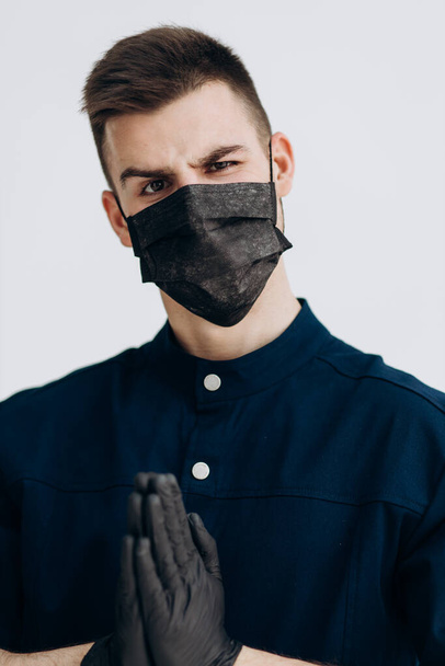Male doctor in black gloves puts on mask against covid - Foto, imagen