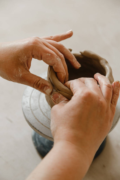 伝統的なスタイルでカップを作る陶芸家の女性の手。手は粘土から料理を作る - 写真・画像