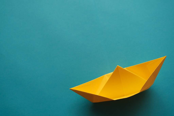 yellow origami paper boat on a blue background - 写真・画像