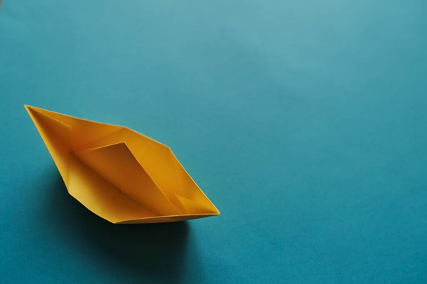 yellow origami paper boat on a blue background - Photo, Image