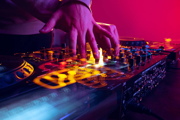 Close-up image of male hands, dj making sounds at night club party with professional sound mixer - Fotó, kép