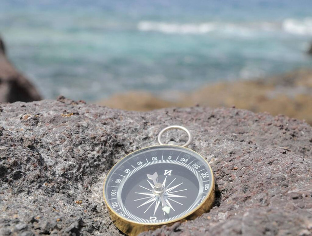 Один компас на скалах у Атлантического океана
 - Фото, изображение