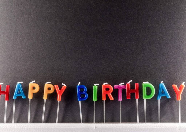 Veel gekleurde kaarsen met tekst Gelukkige verjaardag - Foto, afbeelding
