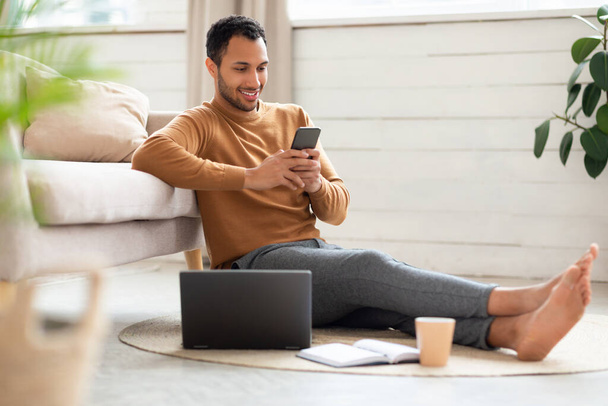 Portrait of smiling man using smartphone and pc at home - Foto, Imagem
