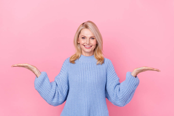 Photo of funny senior blond lady hold empty space wear blue pullover isolated on pink color background - Foto, afbeelding