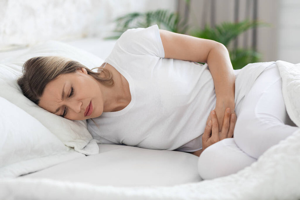 Mujer enferma que sufre de dolor abdominal en la mañana - Foto, Imagen