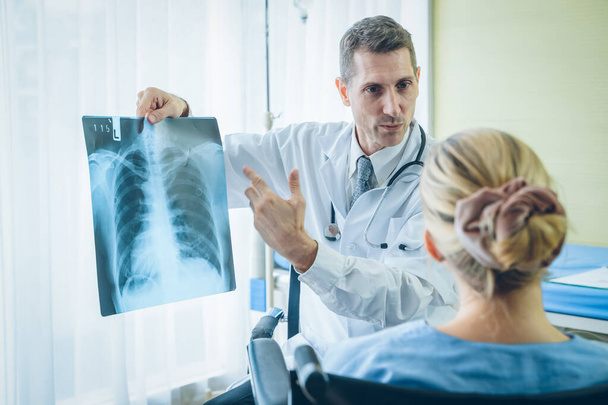 Médico explicando resultados de rayos X al paciente en el hospital, concepto de advertencia pandémica covid virus Corona, 2019-nCoV
. - Foto, imagen