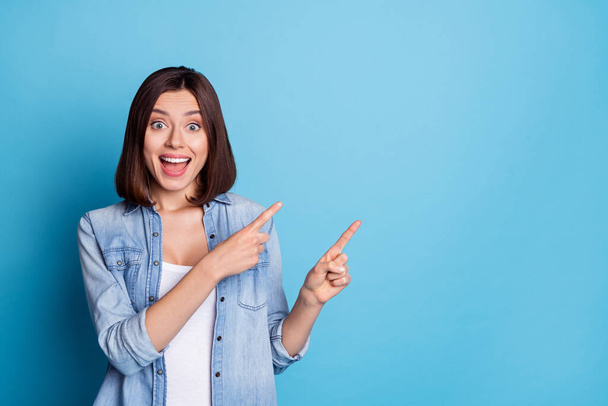 Photo of excited sweet lady dressed denim shirt pointing two fingers empty space isolated blue color background - Φωτογραφία, εικόνα