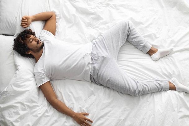 Top view of eastern guy sleeping alone in bed - Photo, Image