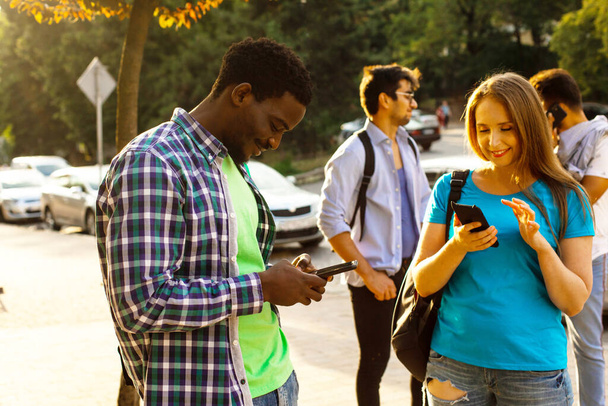 Los estudiantes multiétnicos con teléfonos inteligentes están navegando en Internet - Foto, imagen