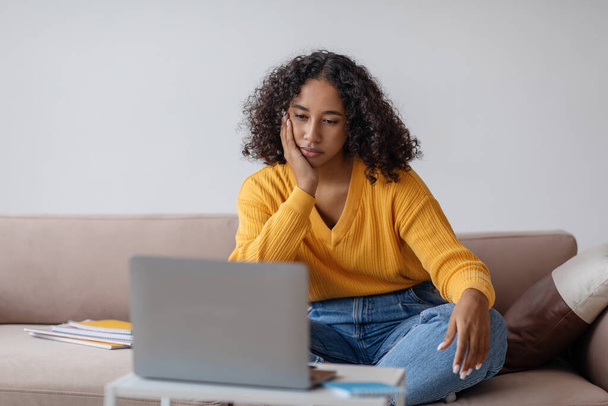 Millennial black woman feeling bored near laptop during online business meeting at home office, copy space - Photo, Image