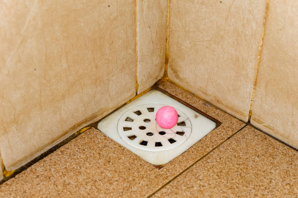afvoergat in badkamer met bruine tegelvloer - Foto, afbeelding