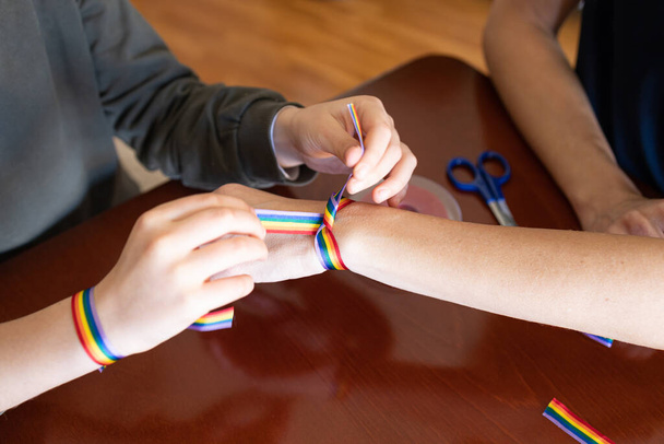 Young girl putting a LGBT rainbow bracelet on a woman's wrist - Fotoğraf, Görsel
