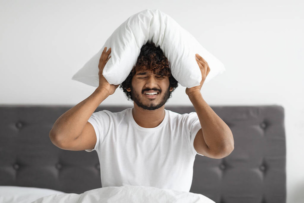 Sick indian guy suffering from headache, sitting in bed - Photo, Image