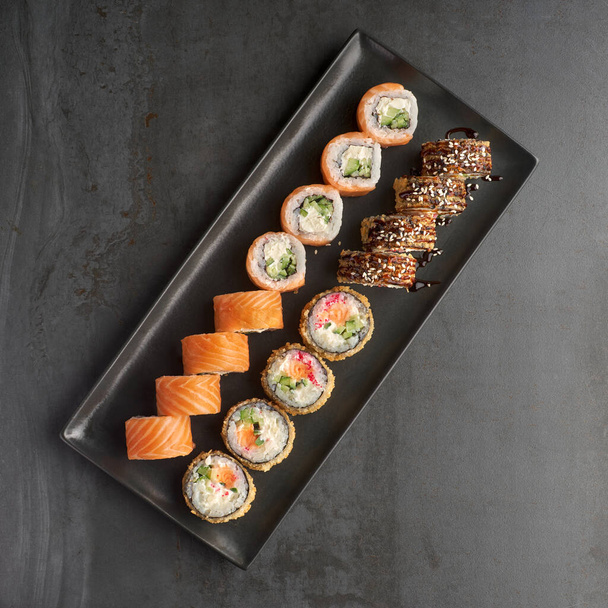 Sushi set. Roll Philadelphia, Tempura Salmon, with fresh ingredients on stone background. Sushi menu. Japanese food. - Фото, зображення
