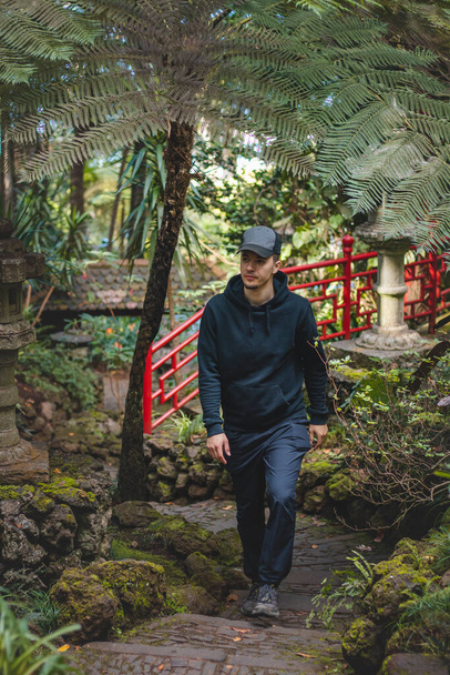 Czarny poszukiwacz przygód spaceruje po ogrodzie botanicznym Monte Palace Madera w Funchal, stolicy portugalskiej wyspy. Piękno rzadkich roślin. - Zdjęcie, obraz