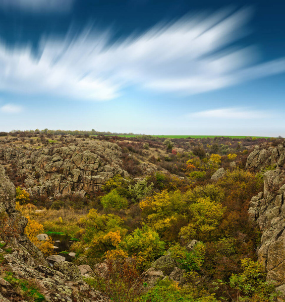 Eine große Anzahl von Steinmineralien mit grüner Vegetation bedeckt liegt über einem kleinen Fluss in der malerischen Ukraine und seiner schönen Natur - Foto, Bild