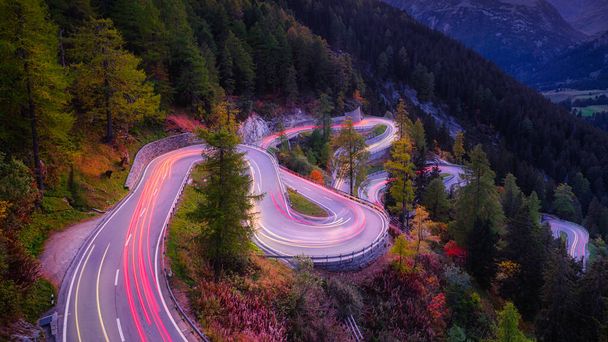 Maloja pass, Switzerland. A road with many curves among the forest. A blur of car lights. Landscape in evening time.  - Photo, Image