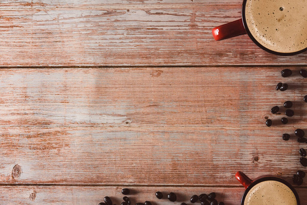 Червоні чашки кави з кавовими зернами на старовинній дерев'яній поверхні. Копіювати простір. Вибірковий фокус
. - Фото, зображення
