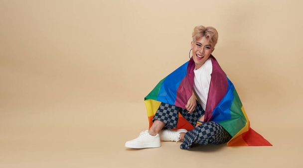 Gioventù asiatica transgender LGBT con bandiera arcobaleno sulla spalla isolata su sfondo di colore nudo. espressione di genere orgoglio e concetto di uguaglianza. - Foto, immagini