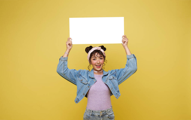 Emocionado chica adolescente asiática sosteniendo burbujas de habla en blanco sobre fondo amarillo. - Foto, imagen
