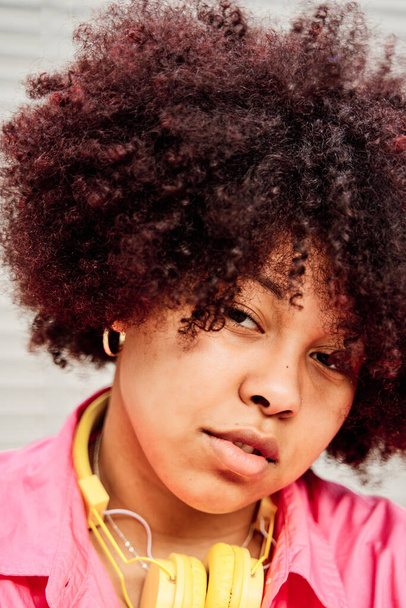κοντινό πλάνο μιας Αφρο-Αμερικανίδας με σγουρά μαλλιά που κοιτάζει την κάμερα. - Φωτογραφία, εικόνα