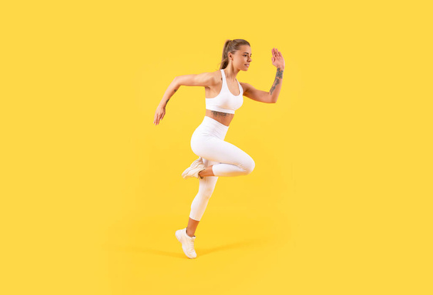 fitness girl jumping in sportswear on yellow background - Photo, image