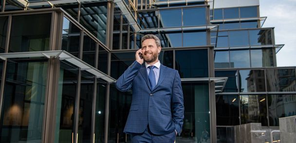 щасливий зрілий бізнесмен в формальному одязі розмовляє по телефону на відкритому повітрі, розмова
 - Фото, зображення