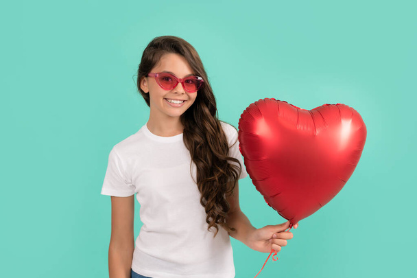 gelukkig kind in zonnebril houden rood hart partij ballon voor Valentijnsdag liefde symbool, lieverd - Foto, afbeelding