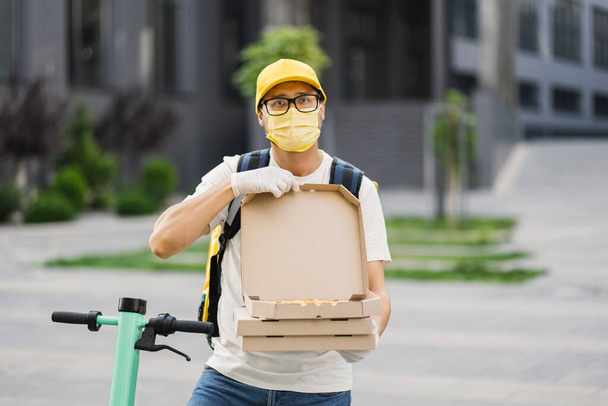 Delivery courier offering the pizza in cardboard boxes. - Photo, image