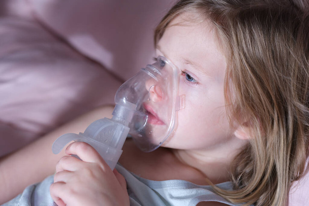 Sick little child in medical oxygen mask lying in bed - Foto, afbeelding