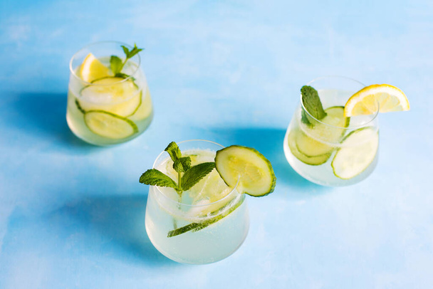 Summer refreshing cocktails with cucumber and lemon slices garnished with mint leaves. View from above. Detox drinks. Drinks for vegetarians.Healthy food concept - Foto, afbeelding