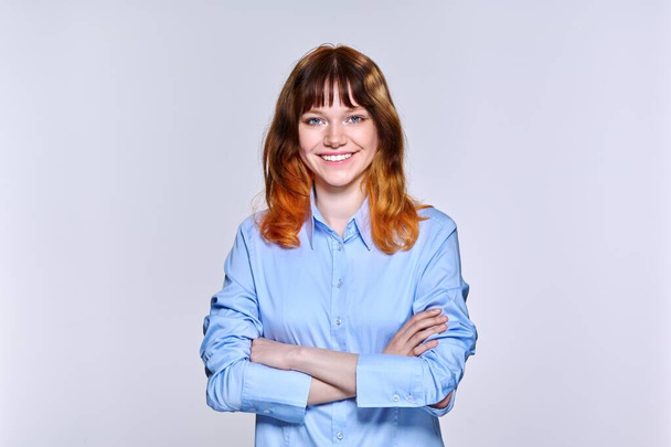 Portrait of young red-haired female looking at camera on light studio background - Φωτογραφία, εικόνα