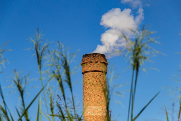 Промышленные трубы, излучающие густой белый дым. Отработанный вентилятор, излучающий дым с голубым небом на заднем плане. - Фото, изображение