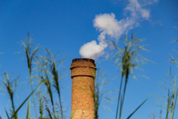 Industrial chimneys emitting dense white smoke. Industry exhaust fan emitting smoke with blue sky in the background. - Zdjęcie, obraz
