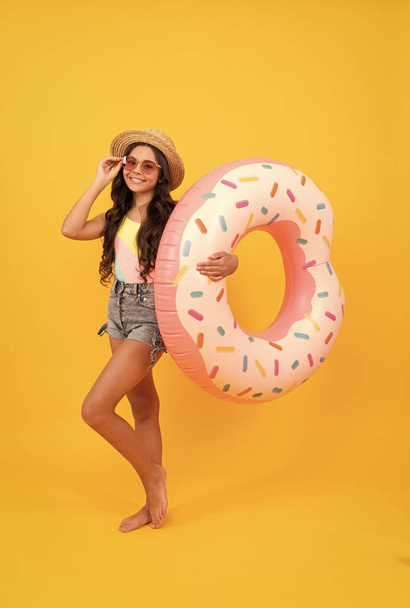 letnie wakacje. szczęśliwa dziewczyna w słomkowym kapeluszu i okulary nadmuchiwane pierścień pączka. - Zdjęcie, obraz